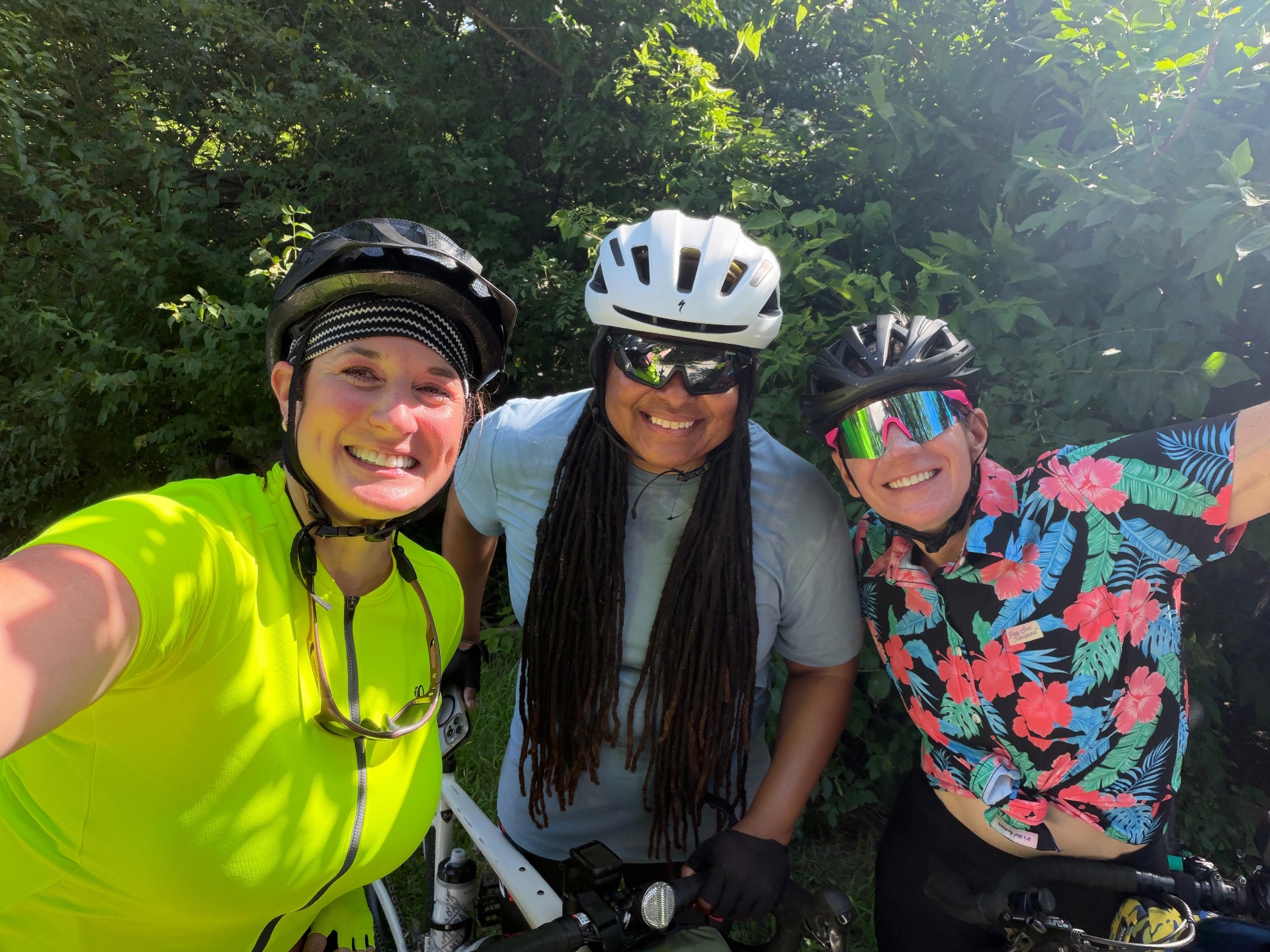 Three smiling More Than Miles riders in helmets and riding gear taking a selfie together on a group ride